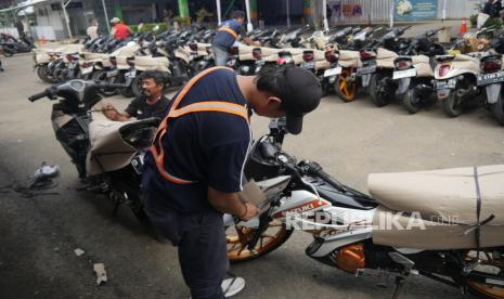 Petugas membungkus motor yang akan dikirim ke luar daerah melalui program Angkutan Motor Gratis (Motis) 2024. DJKA sebut 12.733 sepeda motor diangkut dalam program mudik gratis tahun ini.