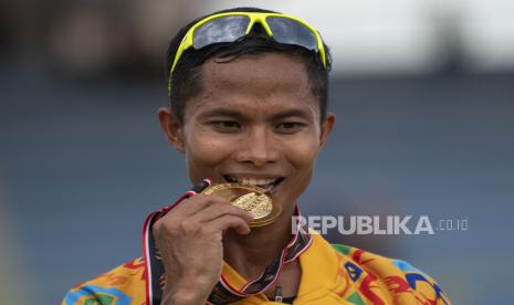 Pelari Nusa Tenggara Barat Ridwan menggigit medali usai menjuarai final lari 1.500 meter putra PON Papua di Stadion Atletik Mimika Sport Center, Kabupaten Mimika, Papua, Senin (11/10/2021). Ridwan meraih medali emas, sementara pelari Bangka Belitung Robi Sianturi meraih medali perak dan pelari Gorontalo Moh. Hadrin Mahdang meraih medali perunggu. 