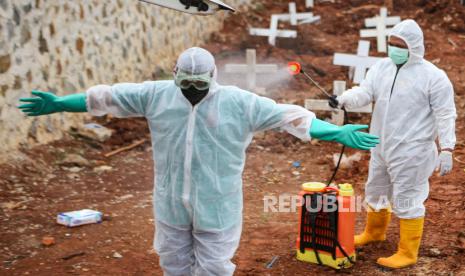 Petugas menyemprotkan cairan disinfektan usai memakamkan jenazah dengan protokol COVID-19 di TPU Jombang, Kota Tangerang Selatan, Banten, Senin (18/1/2021). TPU Jombang membuka blok baru untuk pemakaman jenazah COVID-19 setelah sebanyak 494 liang lahat sudah terisi.