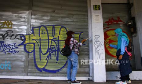 Relawan membersihkan coretan vandalisme di dinding sepanjang kawasan wisata heritage Kayutangan, Malang, Jawa Timur, Ahad (10/10/2021). Kegiatan tersebut untuk mempersiapkan pembukaan kembali kawasan wisata heritage setelah ditutup hampir dua tahun akibat pandemi COVID-19.