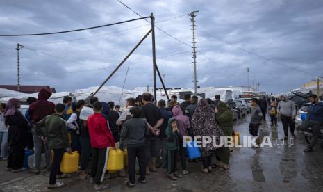 Warga Palestina yang mengungsi akibat pemboman Israel di Jalur Gaza mengantri untuk mendapatkan air di kamp pengungsian PBB di kota selatan Khan Younis, Jalur Gaza, Ahad, (19/11/2023).