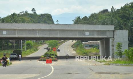 Pengendara melintas di bawah bangunan jembatan tol Padang - Pekanbaru yang belum selesai di Parik Malintang, Kabupaten Padangpariaman, Sumatera Barat, Senin (23/08/2021). Berdasarkan surat Badan Pengatur Jalan Tol (BPJT) Kementerian PUPR Nomor BM.08-P/598,  pembangunan jalan tol Padang - Pekanbaru hanya sampai Sicincin, sementara sisa ruas jalan tol sepanjang 144 kilometer yang membentang dari Kapalo Hilalang, Padangpariaman ke Pangkalan, Kabupaten Limapuluhkota, pembangunannya ditangguhkan sementara.