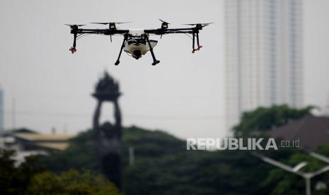 Ilustrasi Sebuah drone (pesawat tanpa awak) menyemprotkan cairan disinfektan.