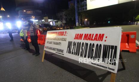 Polisi berjaga di ruas jalan Ahmad Yani yang ditutup saat pemberlakuan jam malam di Kota Banjarmasin, Kalimantan Selatan, Selasa (28/4/2020) malam. Untuk memaksimalkan Pembatasan Sosial Berskala Besar (PSBB) di Kota Banjarmasin pihak Kepolisian Resor Kota Banjarmasin memperketat pemberlakuan jam malam dengan dilakukan penyekatan jalan masuk ke dalam kota dengan akses terbatas dan jalan keluar kota ditutup pada pukul 00