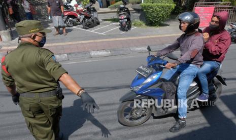 Petugas menghentikan pengendara sepeda motor yang tidak menggunakan masker saat penerapan Pembatasan Kegiatan Masyarakat (PKM) di wilayah Desa Adat Panjer, Denpasar, Bali, Kamis (28/5/2020). Jumlah pasien sembuh dari infeksi Covid-19 di Bali terus bertambah.