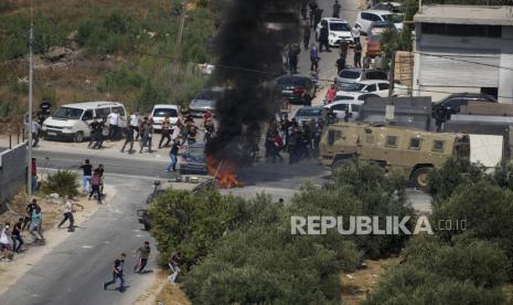 Warga Palestina melemparkan batu ke kendaraan militer Israel selama operasi militer Israel di desa Rujib Tepi Barat, Selasa, 30 Agustus 2022. Tentara mengatakan bahwa mereka menangkap 12 warga Palestina selama penggerebekan Tepi Barat pada hari Selasa, termasuk dua pria yang diduga melakukan penyerangan. penembakan minggu lalu. Mereka ditangkap setelah baku tembak dengan pasukan Israel di desa Rujib, Tepi Barat utara, dekat Nablus.