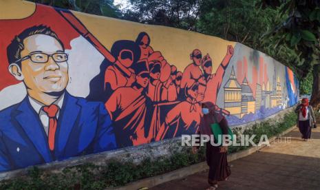  Ridwan Kamil Persilakan Citayem Fashion Week Pindah ke Rawa Kalong. Foto:  Warga berjalan di samping tembok yang dilukis mural di kawasan objek wisata Situ Rawa Kalong, Depok, Jawa Barat, Senin (30/5/2022). Pemerintah Provinsi Jawa Barat membuat mural tersebut sebagai promosi wisata sekaligus menambah daya tarik bagi wisatawan yang berkunjung ke Situ Rawa Kalong. 