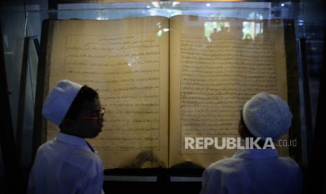 Anak-anak melihat mushaf Alquran raksasa yang dipajang di Masjid Jami Matraman, Jakarta, Selasa (4/4/2023). Masjid tersebut menyimpan empat buah mushaf Al Quran raksasa berukuran 2x1,5 meter yang terbuat dari kertas kuno dan daun lontar.