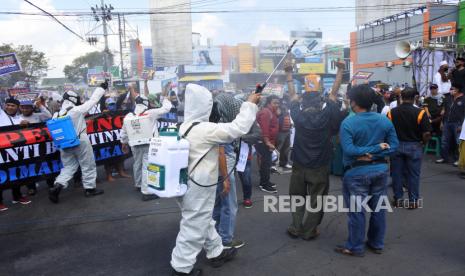 Petugas menyemprotkan cairan disinfektan ke warga yang tergabung dalam Aliansi Masyarakat Jember (AMJ) saat melakukan aksi mendukung DPRD Jember untuk menjalankan hak menyatakan pendapat (HMP) pemberhentian bupati Jember dari jabatan di bundaran DPRD Jember, Jawa Timur, Rabu (22/7/2020). 