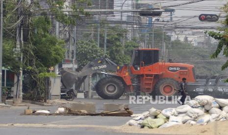 Seorang petugas polisi Myanmar dengan senapan mengamankan daerah itu saat buldoser menyingkirkan barikade pembatas jalan yang didirikan oleh pengunjuk rasa kudeta anti-militer di sebuah jalan di Mandalay, Myanmar, 03 April 2021. Setidaknya 535 orang telah dibunuh oleh militer sejak kudeta, menurut Asosiasi Bantuan untuk Tahanan Politik (AAPP), sementara lebih dari 2.500 orang telah ditahan.