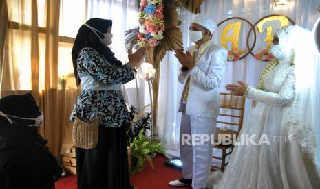 Pasangan pengantin menggunakan masker bersalaman dengan tamu undangan saat resepsi pernikahan di Perumahan Grand Sutera Leuwiliang, Kabupaten Bogor, Jawa Barat, Rabu (22/7/2020). Pemerintah Kabupaten Bogor mengijinkan resepsi pernikahan dan selamatan khitanan dengan sejumlah syarat protokol kesehatan COVID-19 serta pembatasan jumlah tamu undangan saat penerapan PSBB Adaptasi Kebiasaan Baru atau Pra-AKB. ANTARA FOTO/Arif Firmansyah/pras.