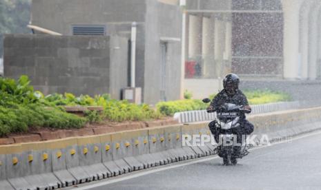 Pengendara motor terkena air yang disemprotkan oleh mobil kepolisian di Jalan Jenderal Sudirman, Jakarta, Rabu (23/8/2023). Penyemprotan di sekitar jalan protokol tersebut sebagai upaya untuk membersihkan debu-debu yang bertebaran di jalanan akibat polusi udara.