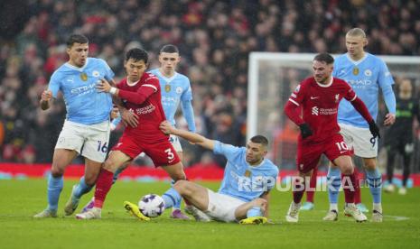 Rodrigo dari Manchester City (kiri) dan Mateo Kovacic (bawah) mencoba menghentikan pemain Liverpool Wataru Endo (tengah) saat pertandingan sepak bola Liga Premier Inggris antara Liverpool dan Manchester City, di stadion Anfield di Liverpool, Inggris, Ahad (10/3/2024).