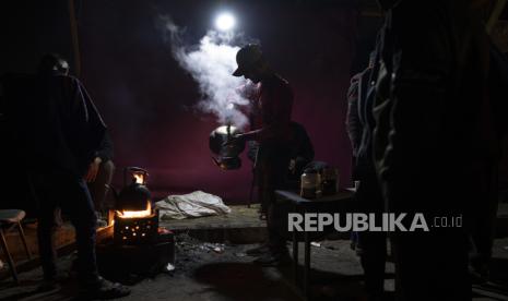 Seorang warga Palestina yang terlantar akibat pemboman Israel di Jalur Gaza menuangkan teh di tenda kamp darurat di daerah Muwasi pada Ahad (31/12/2023).