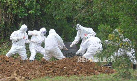 Sejumlah petugas medis memakamkan jenazah pasien positif COVID-19 dengan menggunakan alat pelindung diri (APD) lengkap di Padang, Sumatera Barat, Sabtu (28/3/2020). Pemprov Sumbar mencatat sebanyak 7 orang positif COVID-19 di provinsi itu, 16 orang menunggu hasil dan satu pasien positif warga Padang meninggal