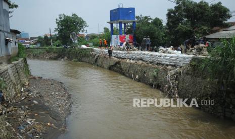 Warga bersama petugas terkait berupaya menambal tanggul Sungai Cigede yang jebol dengan karung berisi pasir di lokasi banjir bandang, di Kampung Lamajang Peuntas, Desa Citeureup, Kecamatan Dayeuhkolot, Kabupaten Bandung, Senin (15/1/2024). Hingga saat ini warga dan petugas terkait masih melakukan penanganan pasca banjir, termasuk penyaluran bantuan untuk korban banjir.