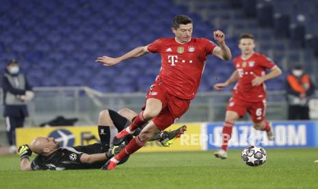 Robert Lewandowski dari Bayern, kanan, menggiring bola melewati penjaga gawang Lazio Pepe Reina dalam perjalanannya untuk mencetak gol selama babak 16 besar Liga Champions pertandingan sepak bola leg pertama antara Lazio dan Bayern Munich di stadion Olimpiade di Roma, Selasa, 23 Februari 2021.