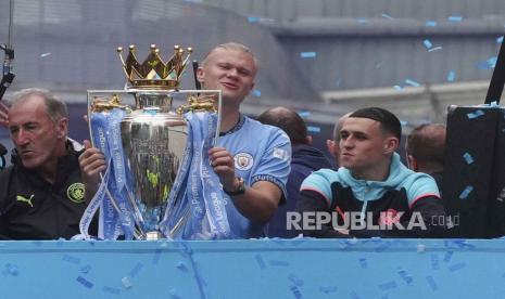 Pemain Manchester City Erling Haaland membawa trofi Liga Premier Inggris di bus atap terbuka selama parade juara di Manchester, Ahad (26/5/2024). Ribuan suporter Manchester City tumpah ruah di jalanan Manchester sambil mengelu-elukan timnya setelah The Citizens memenangkan gelar Liga Premier keempat berturut-turut.