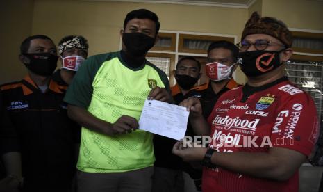 Ketua Komisi Pemilihan Umum (KPU) RI Arief Budiman (kanan) bersama penjaga gawang Persib Bandung Deden M Natshir (tengah) menunjukkan tanda bukti pendaftaran pemilih di Perumahan Soreang Indah Kabupaten Bandung, Sabtu (18/7). Dalam kunjungan kerja tersebut, Arief Budiman memimpin Apel Siaga Nasional Gerakan Coklit Serentak sekaligus memimpin pertemuan secara virtual dengan KPU Kabupaten dan Kota serta meninjau proses Pemutakhiran Data Pemilih. Foto: Abdan Syakura/Republika