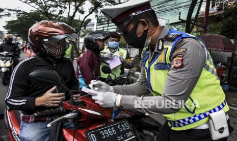 Petugas kepolisian memberikan surat teguran kepada pengendara yang melanggar saat penerapan Pembatasan Sosial Berskala Besar (PSBB) - ilustrasi