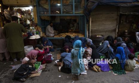  Wanita dan anak-anak Afghanistan duduk di depan toko roti menunggu sumbangan roti di Kota Tua Kabul, Afghanistan, Kamis, 16 September 2021.