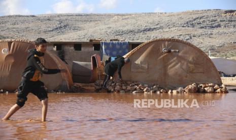 Seorang anak laki-laki berjalan melalui kamp pengungsi yang terendam banjir di provinsi Idlib, Suriah, Selasa, 21 Desember 2021. PBB: 71 Juta Orang Hadapi Kemiskinan Akibat Perang di Ukraina