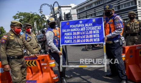 Petugas gabungan membawa papan informasi saat penutupan Jalan Asia Afrika, Kota Bandung, Jumat (18/9). Pemerintah Kota Bandung menutup sejumlah ruas jalan diantaranya Jalan Asia Afrika - Tamblong, Jalan Otista - Suniaraja, Jalan Purnawarman - Martadinata, Jalan Merdeka - Riau dan Jalan Merdeka - Aceh pada pagi dan malam hari guna meminimalisir kerumunan pada masa Adaptasi Kebiasaan Baru (AKB) yang diperketat. Foto: Abdan Syakura/Republika