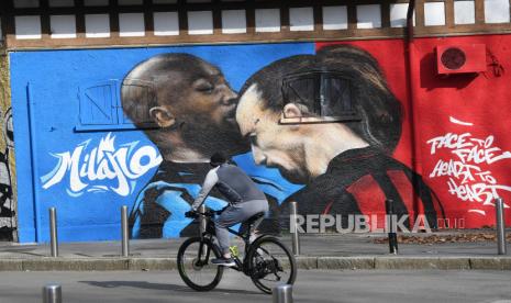 Seorang pengendara sepeda melihat mural di dekat Stadion Giuseppe Meazza, yang menggambarkan Romelu Lukaku (kiri) dari Inter Milan dan Zlatan Ibrahimovic dari AC Milan bertengkar saat pertandingan Piala Italia, di Milan, Italia, 15 Februari 2021. Inter Milan dan AC Milan akan bermain melawan satu sama lain pada 21 Februari 2021 dalam pertandingan puncak Serie A Italia.