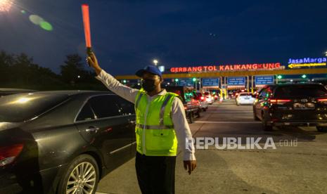 Petugas mengatur arah lajur kendaraan roda empat saat pemberlakuan kebijakan satu arah (one way)  di Gerbang Tol Kalikangkung, Semarang, Jawa Tengah. 