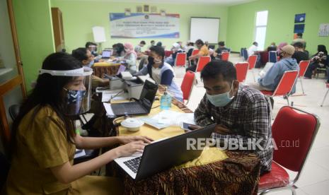 Petugas membatu orang tua murid di posko pelayanan Penerimaan Peserta Didik Baru (PPDB) di SMA Negeri 70, Jakarta, Selasa (16/6). Kendati pelaksanaan PPDB dilaksankan secara daring, namun posko tersebut tetap buat guna membantu orang tua atau calon siswa yang terkendala masalah teknis, dengan tetap menggunakan protokol kesehatan