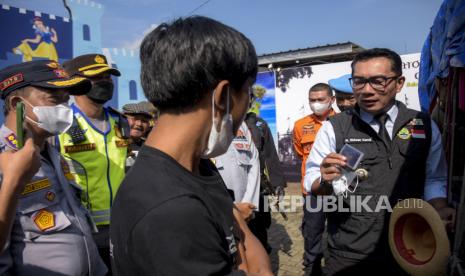 Gubernur Jawa Barat Ridwan Kamil (kanan) memeriksa SIM salah satu pemudik di Pos Terpadu Limbangan, Limbangan, Kabupaten Garut, Jumat (6/5/2022). Peninjauan tersebut bertujuan untuk meninjau secara langsung seluruh pelayanan pos terpadu bagi pemudik serta memastikan keamanan dan kelancaran arus balik Lebaran 2022 yang melalui kawasan tersebut. Foto: Republika/Abdan Syakura