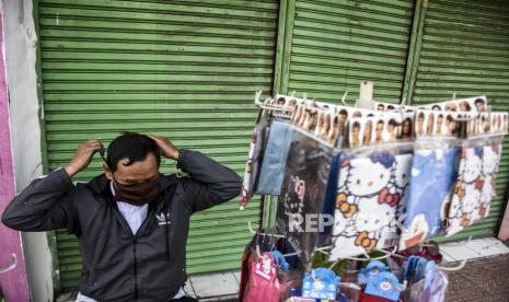 Pedagang masker berbahahan kain menunggu pembeli 