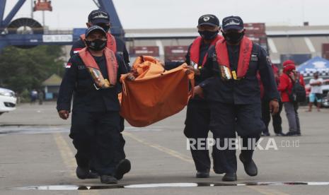 Petugas membawa puing yang ditemukan di perairan sekitar lokasi jatuhnya pesawat penumpang Sriwijaya Air, Sabtu, di pusat komando SAR di Pelabuhan Tanjung Priok, Jakarta, Indonesia, Rabu, 13 Januari 2021. Penyelam mencari pesawat yang jatuh itu. Perekam suara kokpit sedang mencari di lumpur dan puing-puing pesawat di dasar laut antara pulau-pulau Indonesia pada hari Rabu untuk mendapatkan kunci informasi untuk mengetahui mengapa pesawat Sriwijaya Air menukik ke air selama akhir pekan.