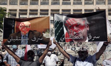 Nasabah bank memegang poster Riad Salameh, gubernur Bank Sentral Lebanon, kanan, dan Makram Sadir, sekretaris jenderal Asosiasi Bank di Lebanon, Rabu 6 Oktober 2021.