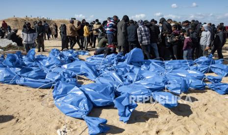 Petugas Kementerian Kesehatan Palestina mempersiapkan jenazah untuk pemakaman massal di kamp Rafah, selatan Jalur Gaza, Selasa (30/1/2024).