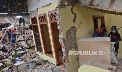 Orang-orang membersihkan puing-puing di sebuah rumah yang rusak berat akibat gempa bumi di Malang, Jawa Timur, Indonesia, Minggu, 11 April 2021. 