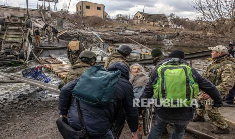  Anggota militer Ukraina bersama dengan orang lain membawa seorang wanita tua di kursi roda untuk menyeberangi jembatan yang hancur ketika orang-orang melarikan diri dari kota garis depan Irpin, wilayah Kyiv (Kiev), Ukraina, 07 Maret 2022. Irpin, kota yang terletak dekat Kota Kyiv mengalami pertempuran sengit selama hampir seminggu antara militer Ukraina dan Rusia yang memaksa ribuan orang melarikan diri dari kota itu.