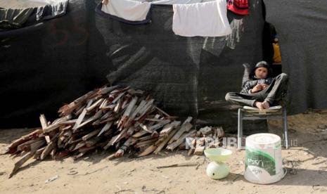 Seorang anak laki-laki Palestina menjual kayu di luar tempat penampungan keluarganya di Rafah, jalur Gaza selatan, (3/1/2024).