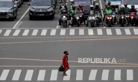  Seorang anak laki-laki memakai masker pelindung saat berjalan melintasi lalu lintas di Jakarta, Rabu (6/1).  Menurut angka terbaru, Indonesia telah mencatat lebih dari tujuh ratus ribu kasus COVID-19 sejak dimulainya pandemi. 