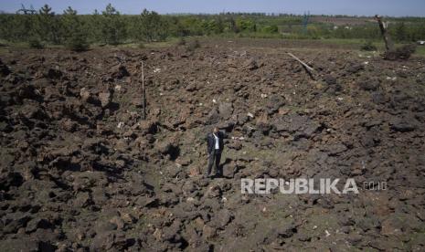 Seorang pria berdiri di kawah ledakan setelah serangan udara Rusia di Bakhmut, wilayah Donetsk, Ukraina, Sabtu, 7 Mei 2022.