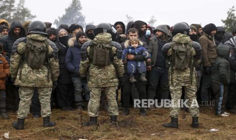 Migran dari Timur Tengah dan tempat lain di depan prajurit Belarusia saat mereka berkumpul di perbatasan Belarusia-Polandia dekat Grodno, Belarus, 14 November 2021. 