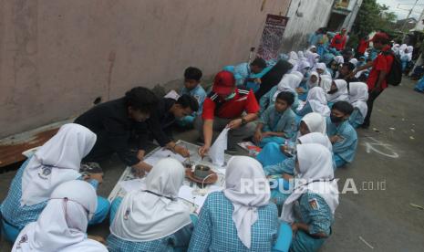 Siswa SMPN 1 Pandaan melakukan pewarnaan batik dengan teknik colet dalam kegiatan Membatik Massal di depan rumah produksi Batik Lintang, Malang, Jawa Timur, Rabu (25/1/2023). Kegiatan tersebut untuk mengenalkan proses pembuatan batik tulis serta pewarnaan kepada 375 peserta yang terdiri dari pelajar, mahasiswa, dan guru. 