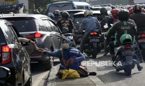 Seorang pengendara memberikan uang kepada pengemis saat terjebak macet. Pj Bupati Bekasi sebut jumlah gelandangan-pengemis di jalan mengalami peningkatan.