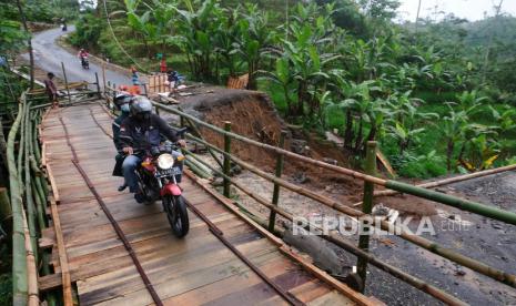 Pengendara sepeda motor melintasi jembatan darurat di lokasi tanah longsor di Wonosobo, Jawa Tengah. Tanah longsor akibat hujan deras mengakibatkan jalan antarkecamatan terputus sehingga warga membuat jembatan darurat yang hanya bisa dilalui sepeda motor dan pejalan kaki (ilustrasi). 