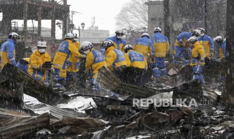 Hujan turun saat petugas polisi mengeluarkan puing-puing dari kebakaran di pasar yang terbakar di Wajima, prefektur Ishikawa, Jepang Sabtu, (6/1/2024).