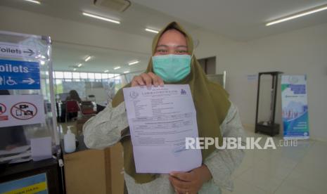 Calon penumpang pesawat udara memperlihatkan hasil rapid test antigen di klinik pelayanan rapid test Bandara Syamsudin Noor, Banjarbaru, Kalimantan Selatan, Selasa (22/12/2020). PT Angkasa Pura I cabang Bandar Udara Syamsudin Noor menyediakan layanan rapid test antigen bagi para calon penumpang pesawat udara dengan tujuan sejumlah daerah yang mewajibkan memperlihatkan hasil rapid test antigen yang menjadi syarat masuk ke daerah tersebut. 