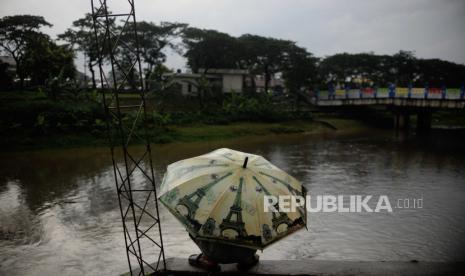 Seorang warga memakai payung saat sedang memancing ikan di kawasan Banjir Kanal Timur, Duren Sawit, Jakarta, Senin (27/3/2023). Badan Meteorologi Klimatologi dan Geofisika memprakirakan hujan masih berpotensi terjadi hingga awal April 2023 mendatang yang disebabkan dinamika atmosfer masih mengalami peralihan dari musim penghujan menuju musim kemarau.