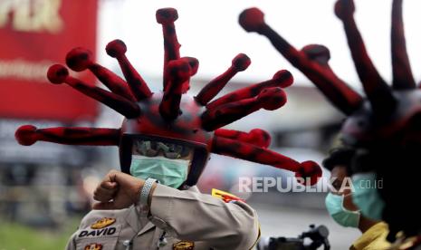 Seorang perwira polisi Indonesia yang memakai helm yang dimodifikasi menyerupai coronavirus, memeriksa arlojinya saat berkampanye akan kesadaran terhadap bahayanya wabah virus, di Mojokerto, Jawa Timur, Indonesia, Jumat, 3 April 2020.