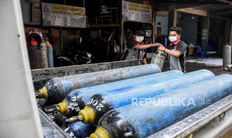 Pekerja mengangkut tabung kosong ke atas mobil di agen isi ulang oksigen