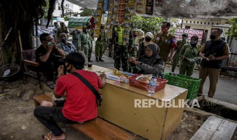 Petugas gabungan membagikan masker saat sosialisasi perpanjangan Pemberlakuan Pembatasan Kegiatan Masyarakat (PPKM) Skala Mikro. 